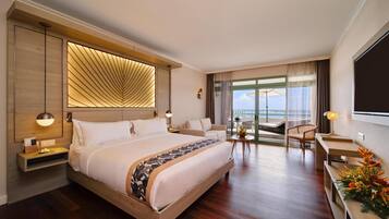 Ein modernes Hotelzimmer mit einem großen Bett, einem Schreibtisch, einem Sessel und einem Balkon mit Aussicht.