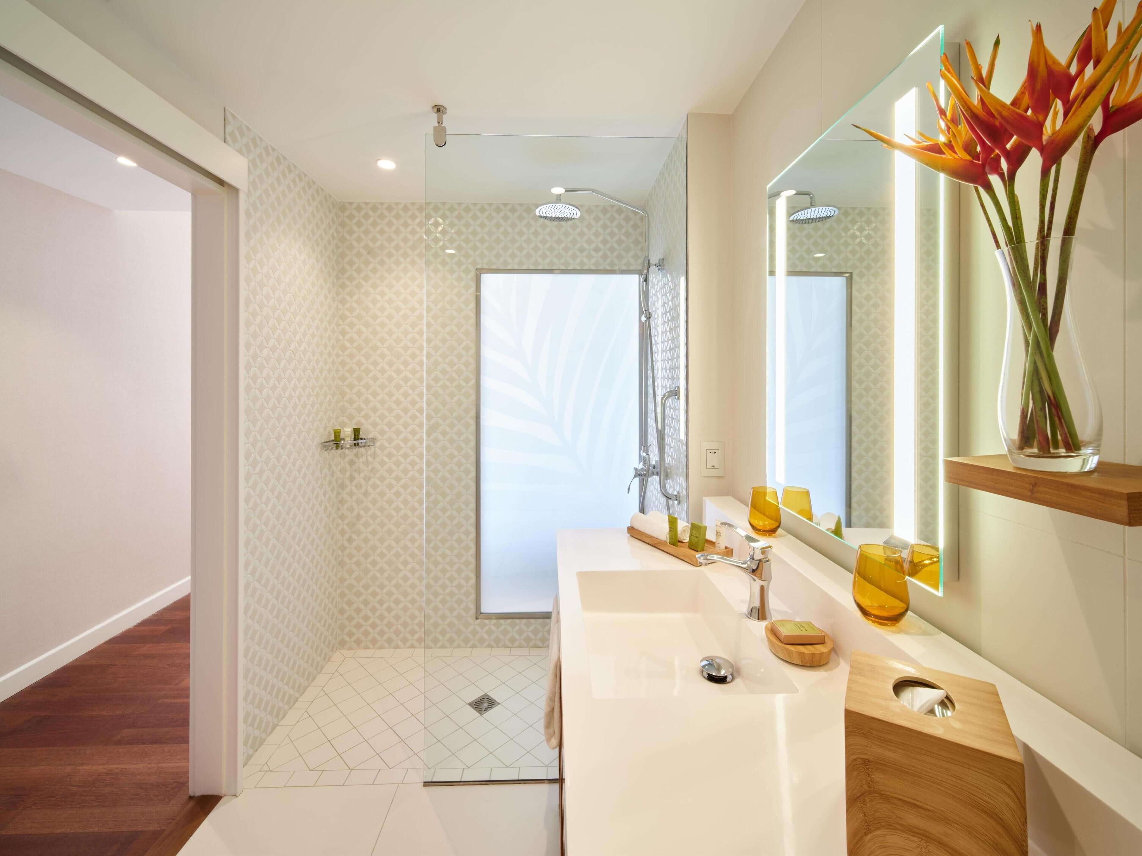 A modern bathroom with a large mirror, a sink, and a shower area.