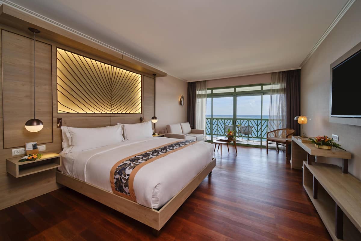 A modern hotel room with a large bed, a balcony with a view, and a flat-screen TV.