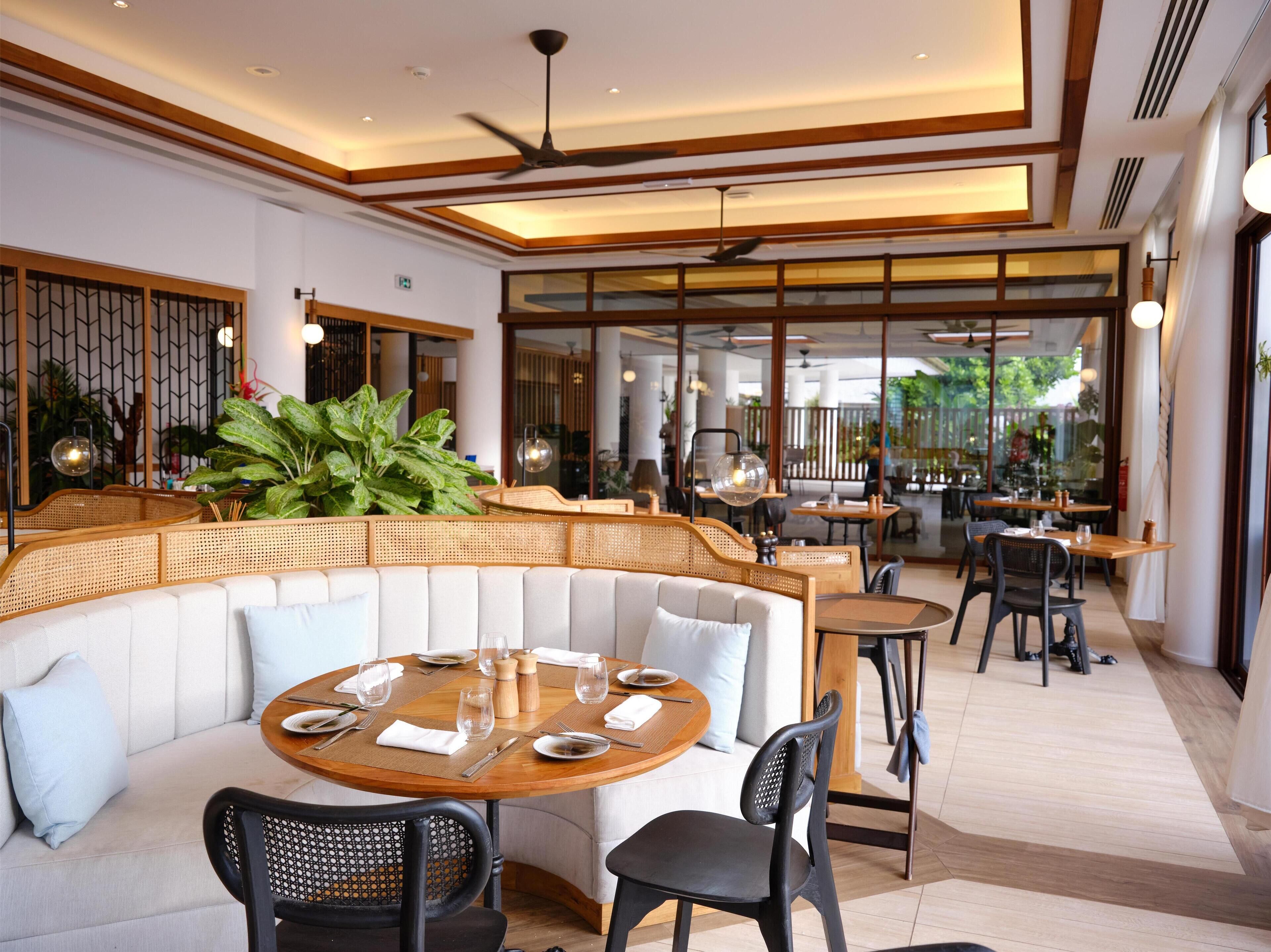 A modern dining area with a round wooden table, black chairs, and a cushioned bench.