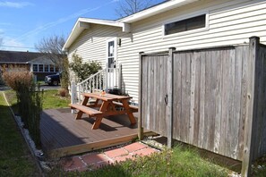 A house with a wooden deck, a picnic table, and a wooden fence.