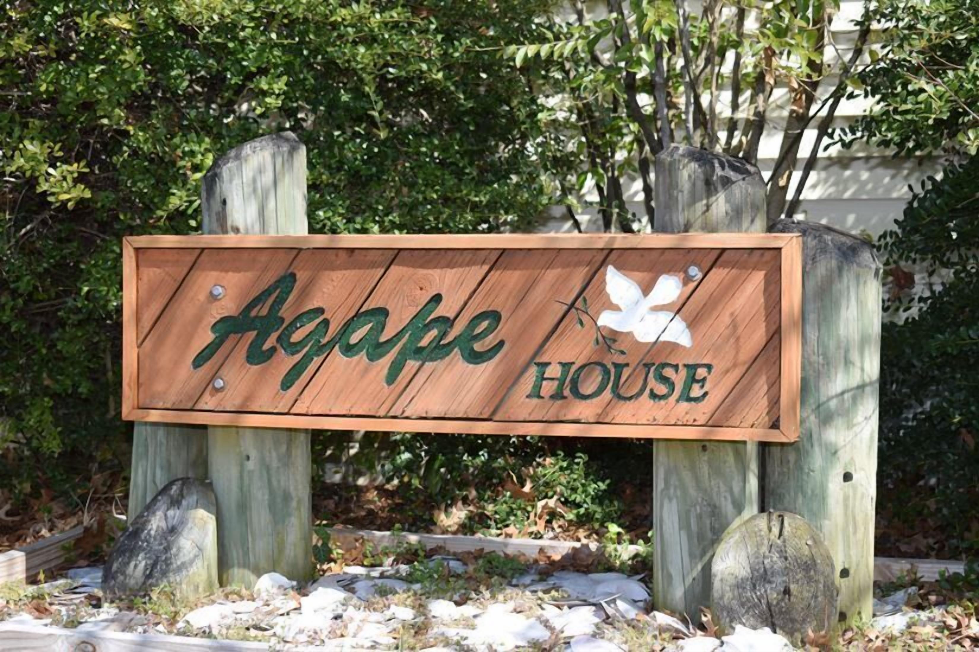 A wooden sign with the text "Agape House" and a white dove symbol.