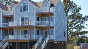 A multi-story residential building with balconies and a wooden deck area. - Allowaves- Luxury Town Home with Community Pool & Fishing Pier (Chincoteague)