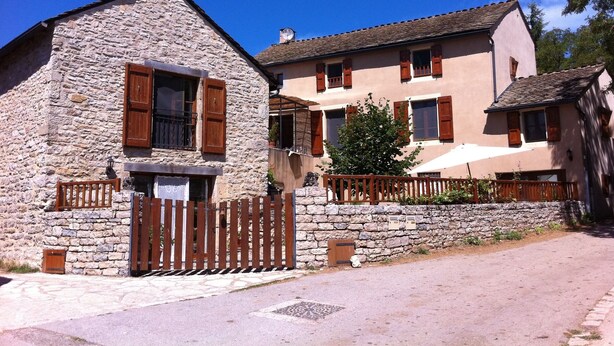 Un edificio de piedra con un portón de madera y un árbol pequeño al frente.