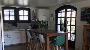 Eine Küche mit einer zentralen Kochinsel, weißen Schränken und einem Essbereich mit Stühlen.