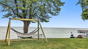 A hammock under a tree by a lake with picnic tables and boats. - Turquoise Beach Cottage (Luxemburg)