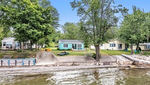 A lakeside property with a small house, a dock, and a boat. - Turquoise Beach Cottage (Luxemburg)