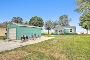 A residential area with a green garage, two bicycles, and a lawn with yellow chairs. - Turquoise Beach Cottage (Luxemburg)