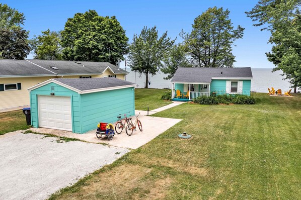 A row of single-story houses with attached garages, a well-maintained lawn, and a view of a lake. - Turquoise Beach Cottage (Luxemburg)