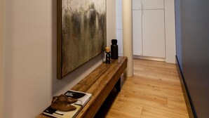 A hallway with a wooden bench, a large abstract painting, and a white wardrobe. - FLH Amazing Praça Comércio Design Flat (Lisbon)