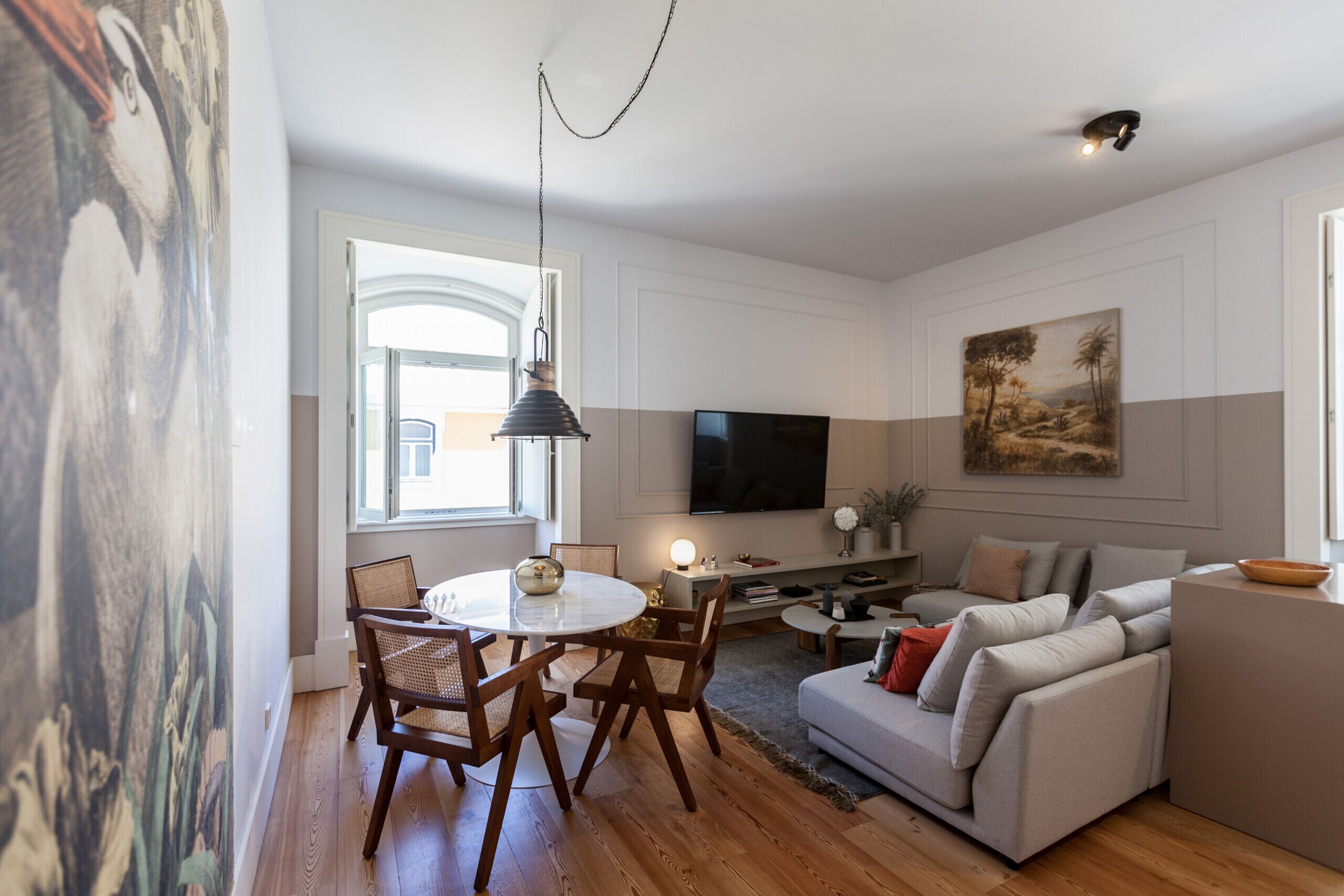 Een moderne woonkamer met een eethoek, een flatscreen televisie en kunstwerken aan de muren.