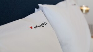 Un coussin orné d’un logo et d’un texte, un coussin bleu foncé et un coussin blanc.