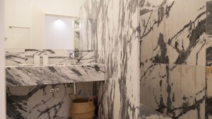 Une salle de bain avec un lavabo en marbre, un miroir et un panier en osier.