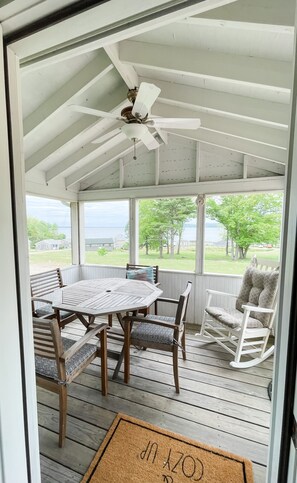 A covered outdoor area with a table and chairs, a rocking chair, and a view of the landscape.