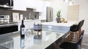 Una cocina moderna con una isla central, electrodomésticos de acero inoxidable y un comedor con sillas.