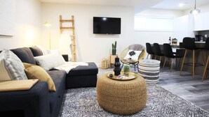 Una sala de estar moderna con un sofá, una mesa de centro y un comedor con sillas y un televisor.