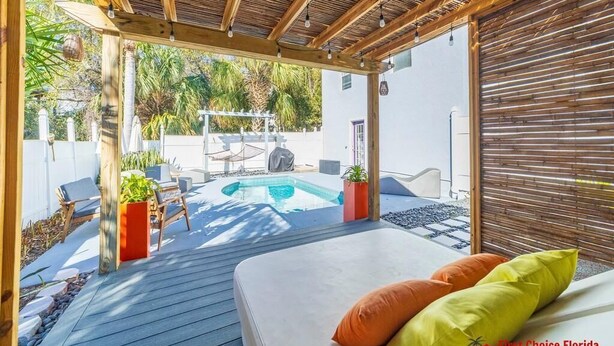 Un patio techado al aire libre con piscina, terraza de madera y zona de estar.