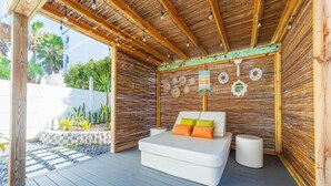 Un dormitorio moderno al aire libre con techo de madera y cama con almohadas coloridas.