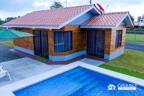 A modern house with a swimming pool, wooden exterior, and large windows.