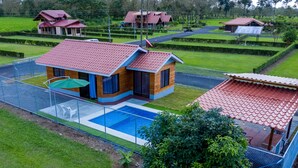 A modern house with a swimming pool, surrounded by a fence, and set in a lush green landscape. - Sunset Arenal House (La Fortuna)