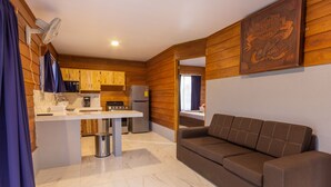 A compact living space with a kitchenette, a sofa, and a mounted Harley-Davidson logo. - Sunset Arenal House (La Fortuna)