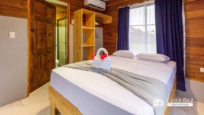 A wooden-paneled room with a bed, a wooden wardrobe, and a window with curtains. - Sunset Arenal House (La Fortuna)