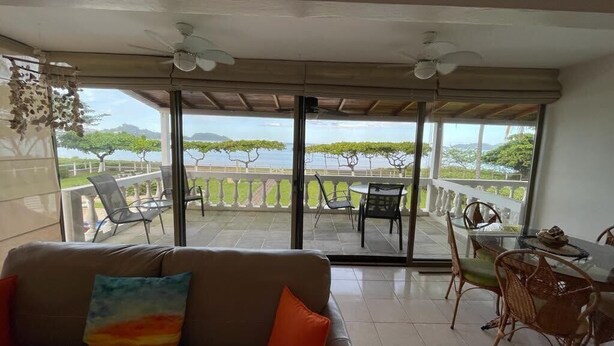 A balcony with a sofa, chairs, and a table. - Beachfront Condo with Pool and Ocean View Playa Potrero, Costa Rica (Surfside (Playa Potrero))