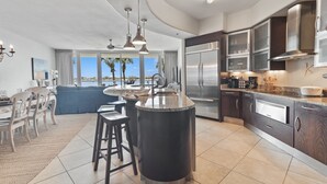 Una cocina moderna con una isla grande, electrodomésticos de acero inoxidable y vista al océano.