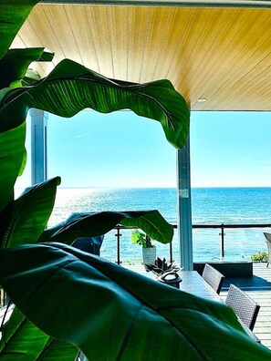 A covered outdoor seating area with a view of the ocean.