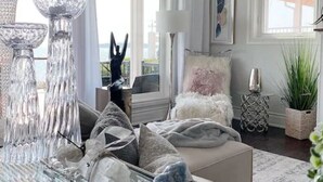 Un salon moderne avec une table basse en verre, des vases décoratifs en verre et un coin salon confortable comprenant un canapé et des fauteuils.