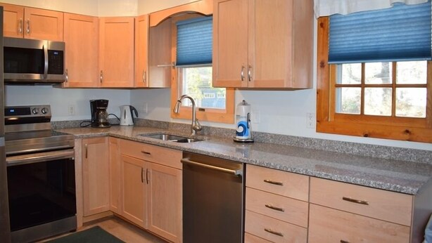 A kitchen with wooden cabinets, a stainless steel microwave, a dishwasher, and a window with blinds. - Aramabad- Close to Beach. Shared Water Access. (Chincoteague)