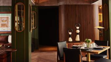 Un comedor moderno con una mesa de madera, sillas tapizadas en negro y un suelo con estampado de espiga.