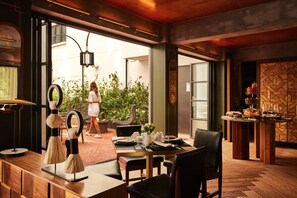 A restaurant with a wooden table set for dining, a bar area with drinks, and a view of the outdoors. - Campos Polanco (Mexico City)
