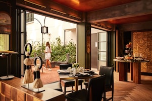 A restaurant with a wooden table set for dining, a bar area with drinks, and a view of the outdoors.