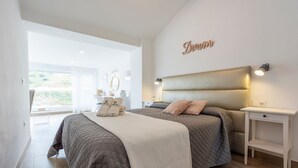 Ein modernes Schlafzimmer mit einem großen Bett, Nachttischen und Blick ins Freie.