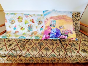 Relax on a stylish sofa with a vibrant, tropical print, complemented by a colorful accent cushion.