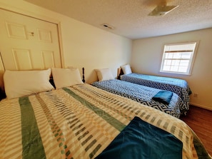 Two single beds with patterned bedding, a door with a decorative element, and a window with blinds.