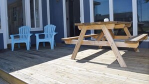 A wooden deck with a picnic table and two blue chairs. - Avocet- Shared Community Water Access, Close to Beach. (Chincoteague)