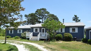 A two-story house with a front porch and a pathway leading to the entrance. - Avocet- Shared Community Water Access, Close to Beach. (Chincoteague)
