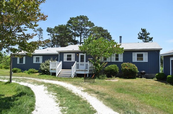 A two-story house with a front porch and a pathway leading to the entrance. - Avocet- Shared Community Water Access, Close to Beach. (Chincoteague)