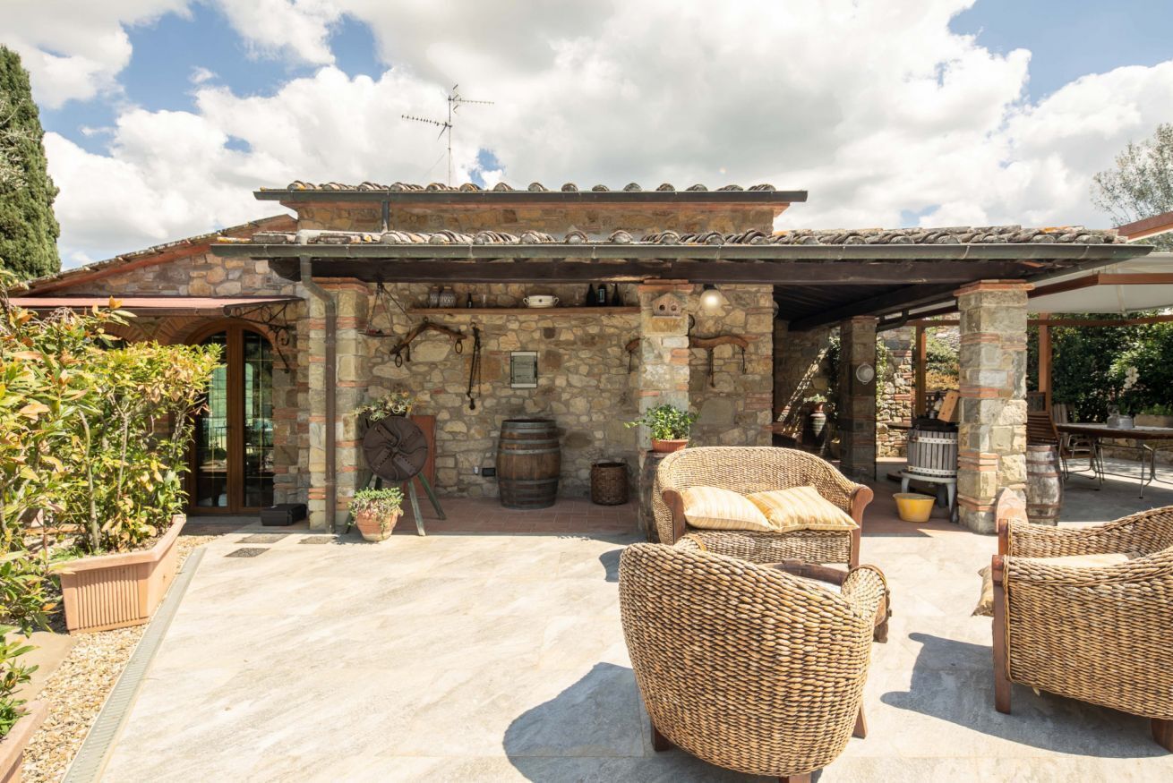 A stone building with a covered patio, wicker furniture, and outdoor seating.