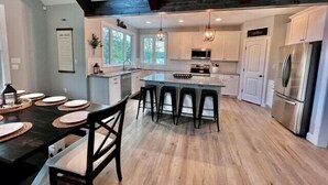 Una cocina moderna con una isla central, taburetes de bar y una mesa de comedor para cuatro.