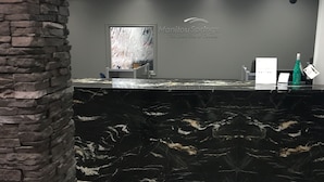 A reception desk with a black marble top, a stone pillar, and a wall-mounted sign reading "Manitou Springs The Dead Sea of Canada". - Manitou Springs Resort (Manitou Beach)