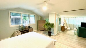 Un dormitorio con cama, cómoda, planta en maceta y ventilador de techo.
