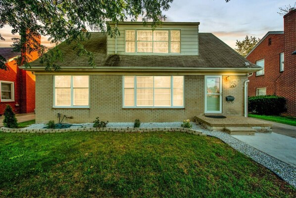 A two-story house with a brick facade, large windows, and a small front porch.