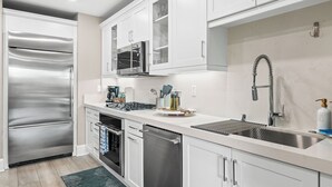 Una cocina moderna con electrodomésticos de acero inoxidable, armarios blancos y microondas integrado.