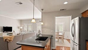 Una cocina moderna con isla integrada, electrodomésticos de acero inoxidable y una zona de comedor con mesa y sillas de madera.