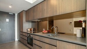 A modern kitchen with wooden cabinetry, stainless steel appliances, and a large island with a sink.
