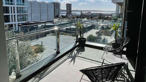 A balcony with a view of a cityscape, including buildings and a body of water.