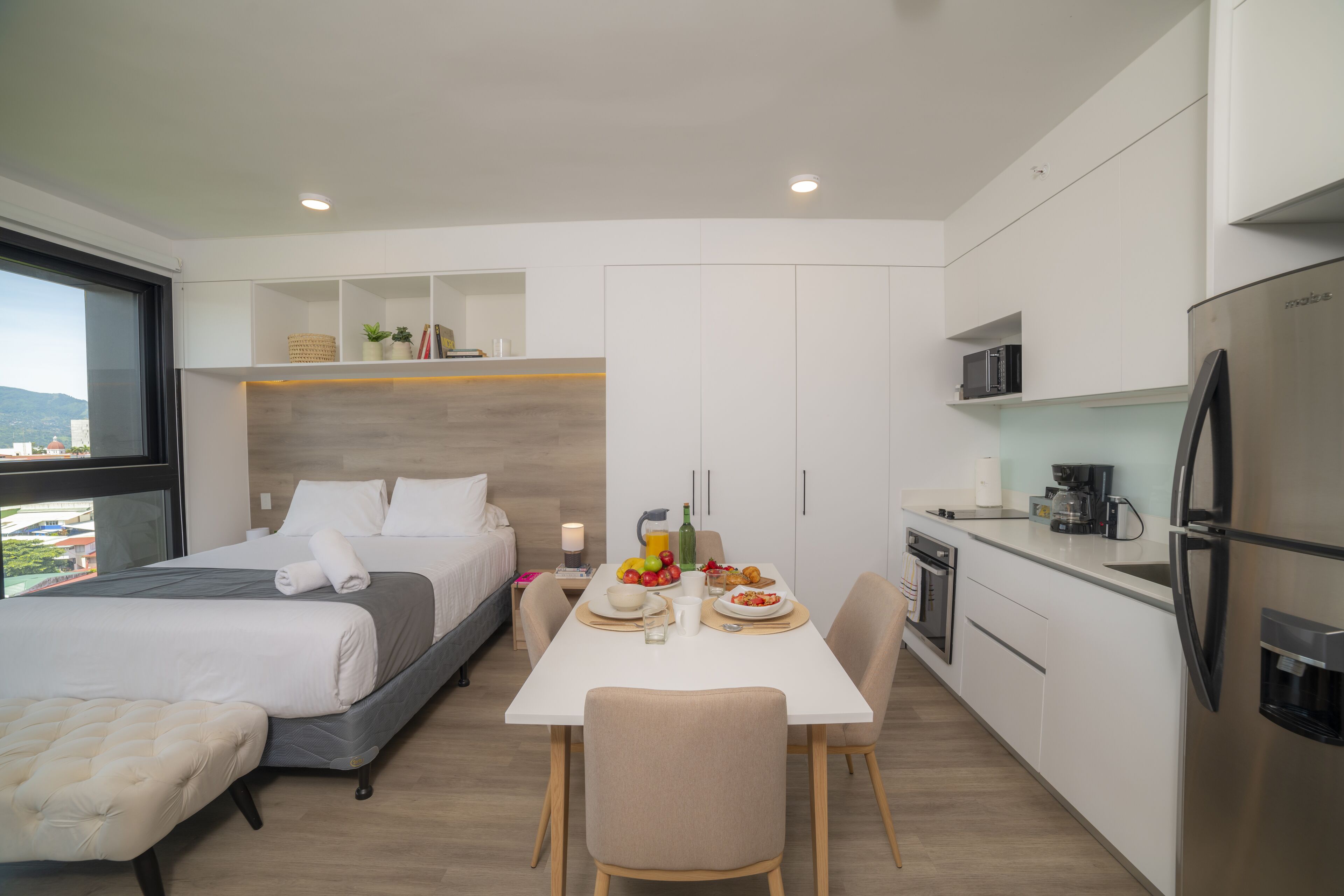 Una camera d'albergo moderna con un letto, un comodino e vista sulla città.